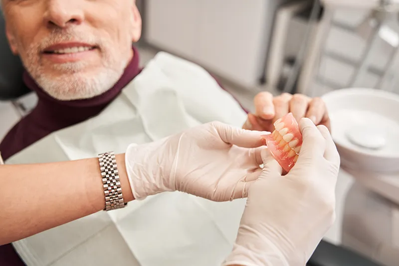 Dentist showing a patient custom dentures during a restorative dentistry consultation in Oklahoma City