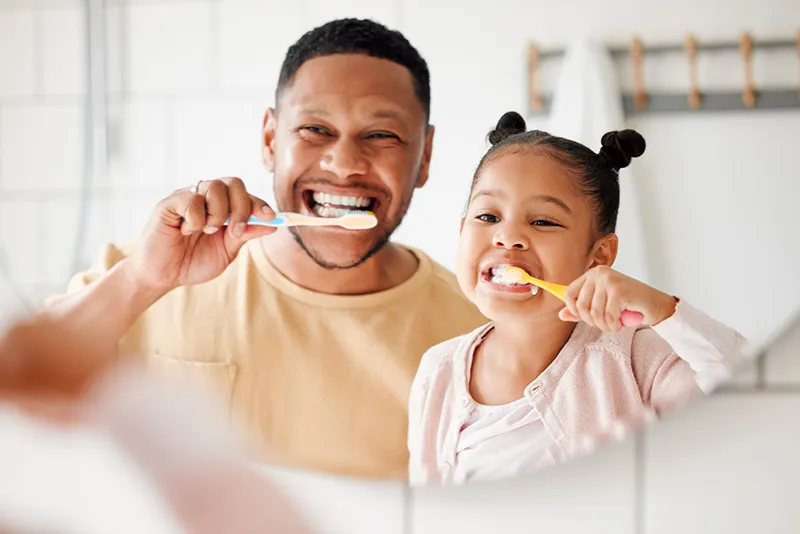 Parent and child brushing their teeth as part of healthy family dental care in Oklahoma City